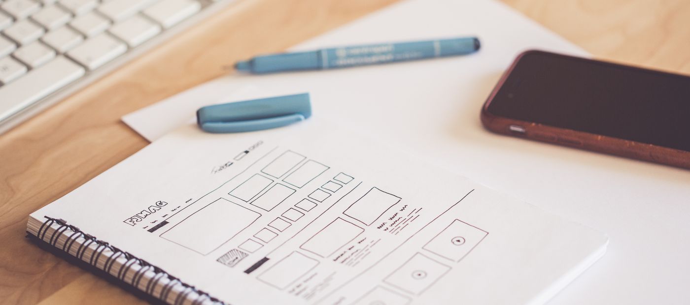 A workspace with wireframe sketches, a phone and a keyboard