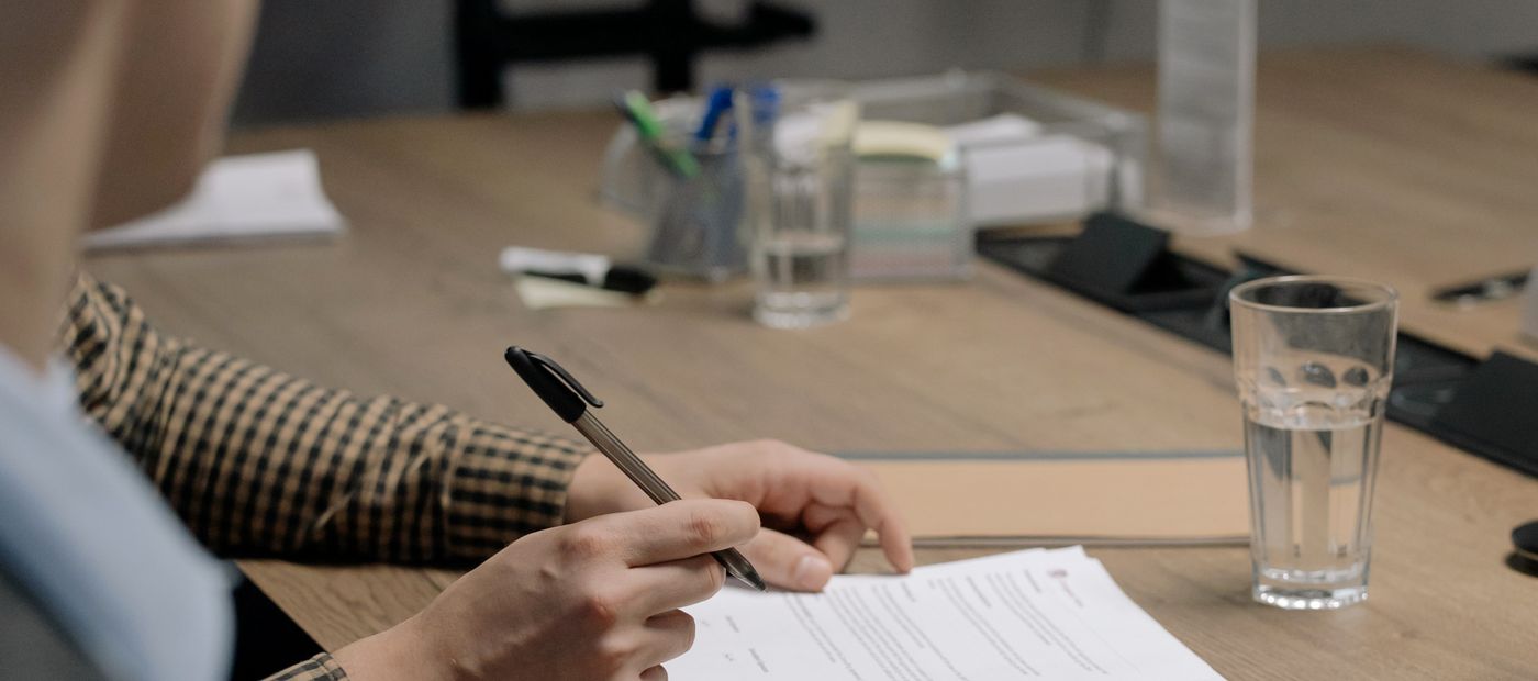 Somebody signing a document at a desk in an office