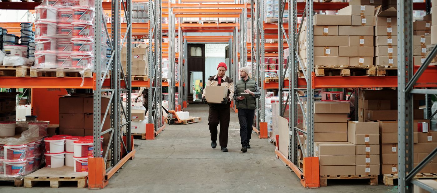 Two workers handling a package in a warehouse aisle