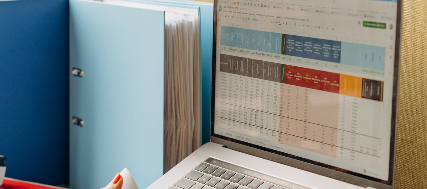 A desk with folders beside a laptop showing an analytics screen