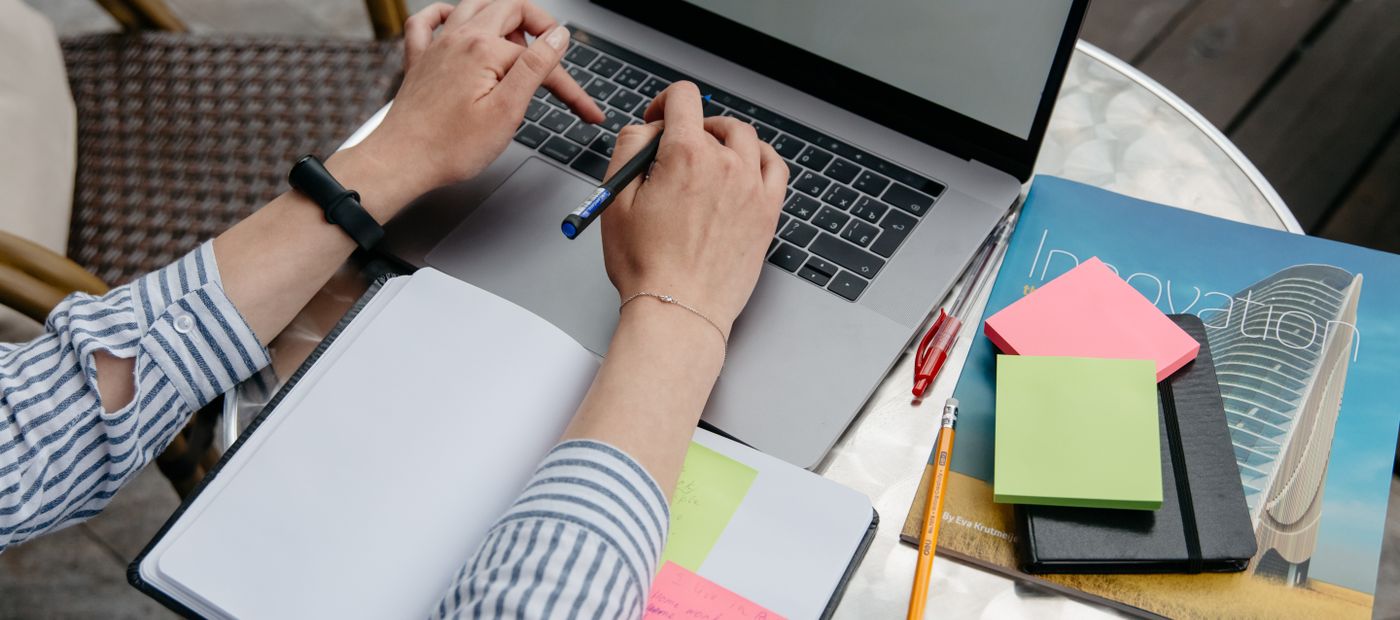 Hands at a laptop with sticky notes and a notebook, working out where a change fits
