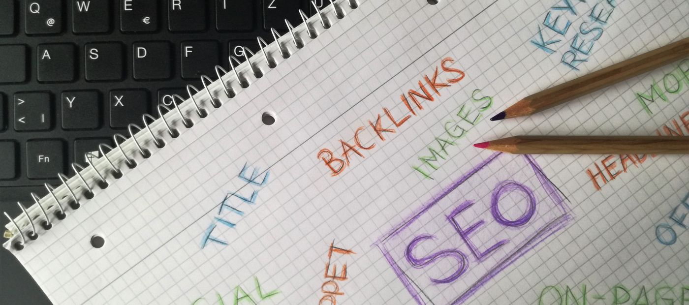 A notebook on a keyboard with SEO, title, backlinks and keywords written by hand