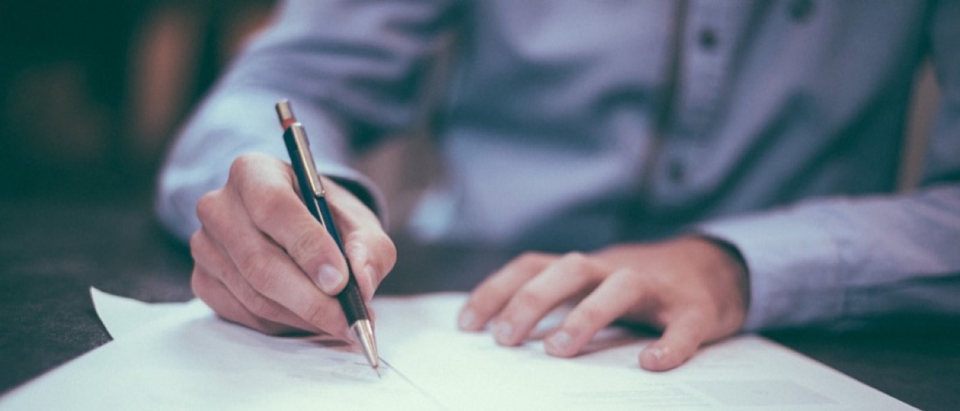 A hand signing a document at a desk