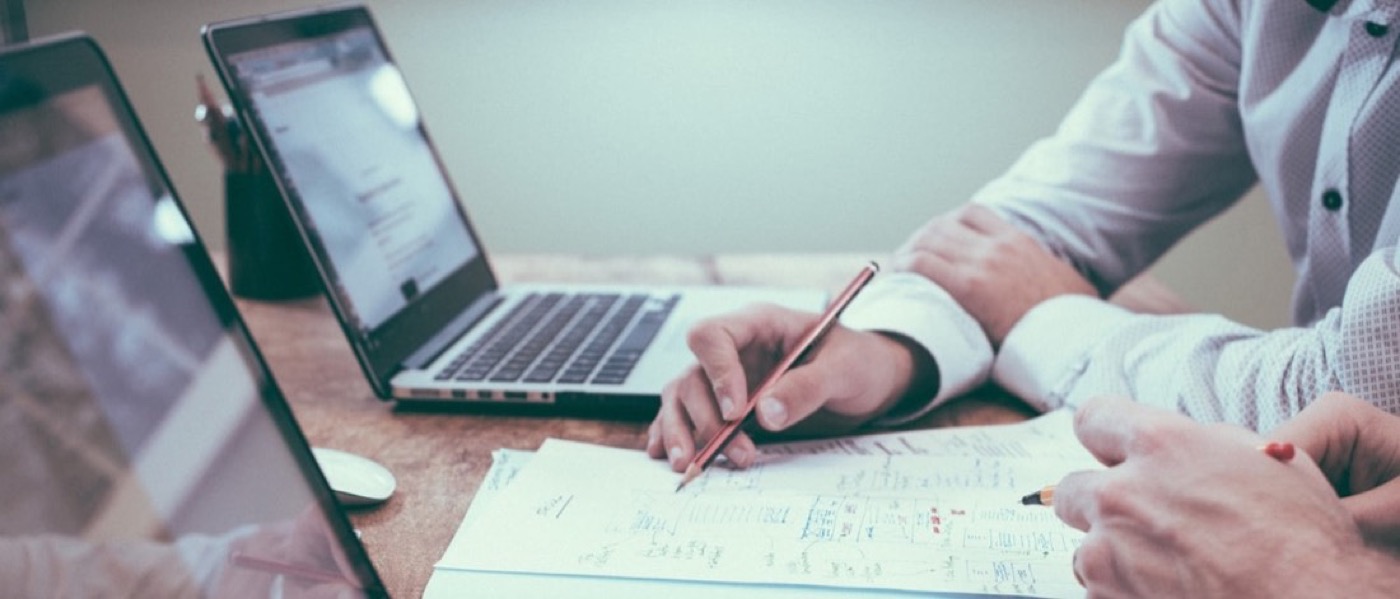 Hands, a laptop and working notes spread across a table