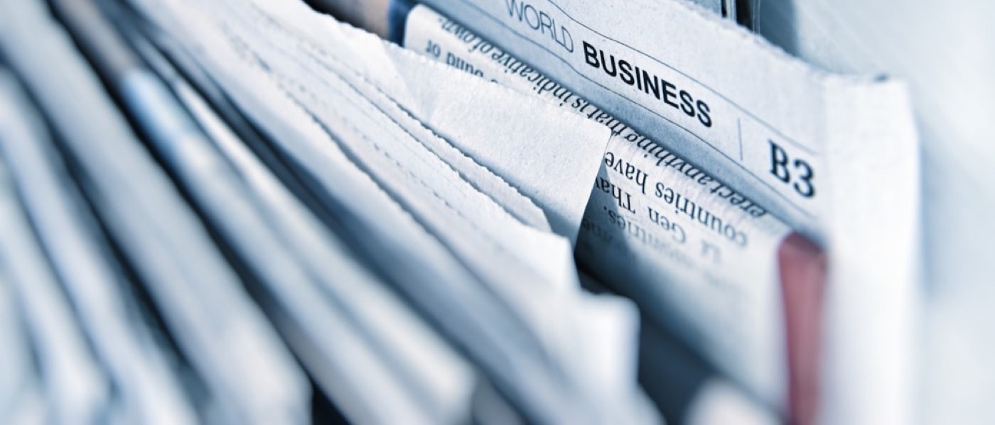 A stack of newspapers open at the business section