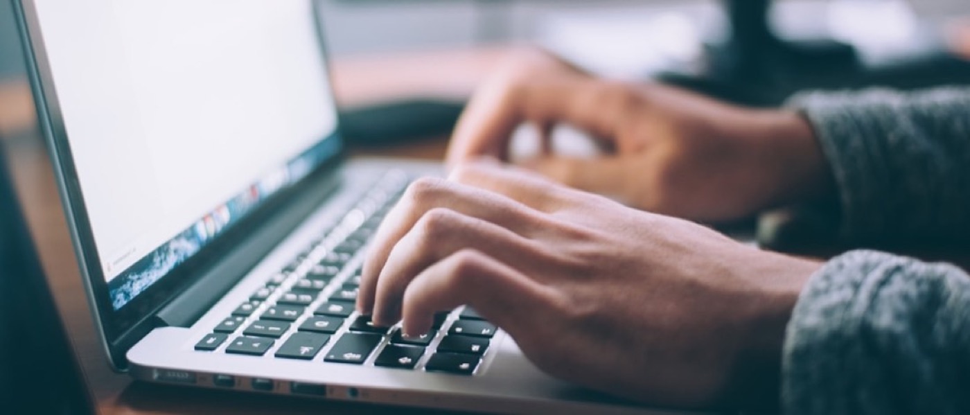 Hands typing on a laptop keyboard